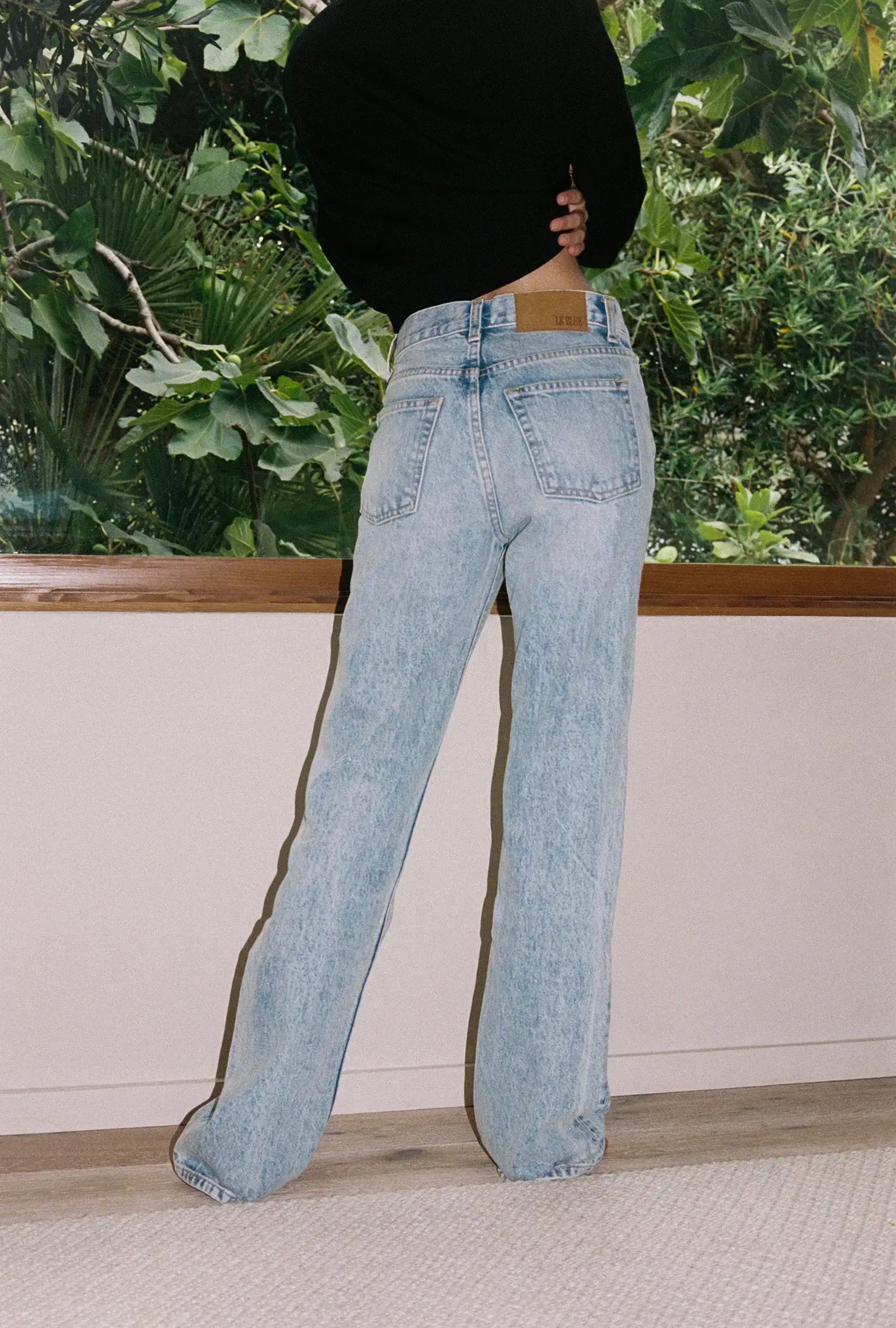 Person wearing light blue jeans with a blurred background