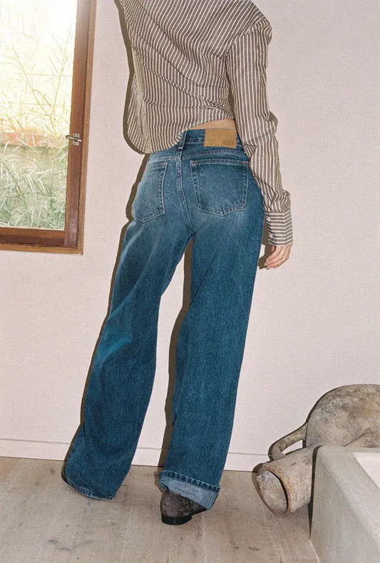 Person wearing blue Kinney low rise baggy jeans by LKblue and a striped shirt in an indoor setting.