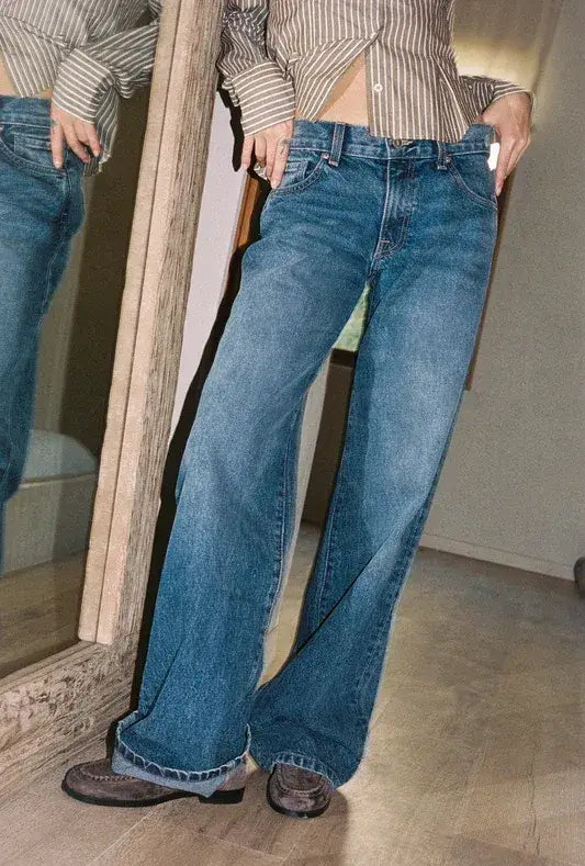 A person wearing blue denim jeans for women standing in front of a mirror.