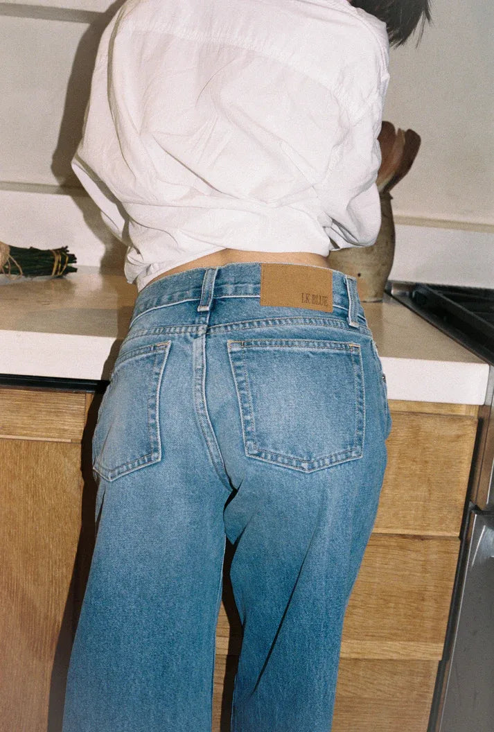 Person wearing blue low rise jeans and a white shirt in a kitchen setting