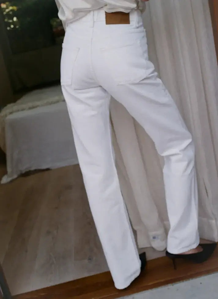 White denim bootcut pants worn by a person in an indoor setting with a neutral background