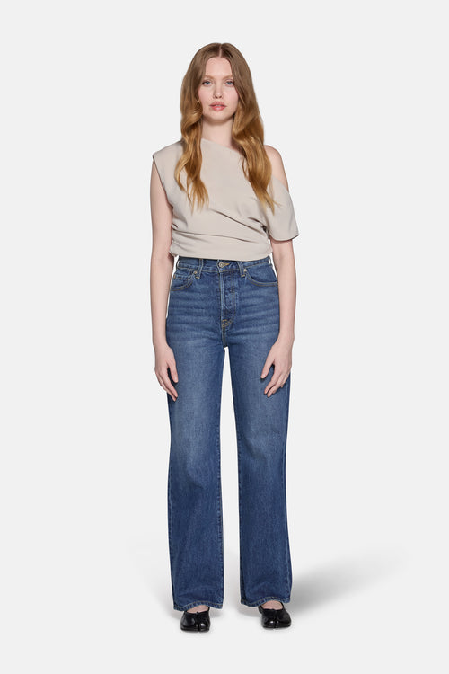 a women with blonde hair wearing yellowish top and modeling for high rise straight leg jeans 
