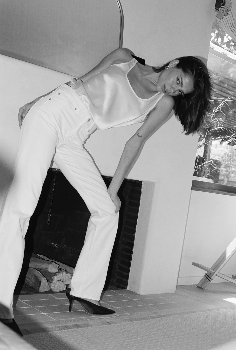A person wearing a white top and white pants from LKBLUE in a room with a couch and a window.