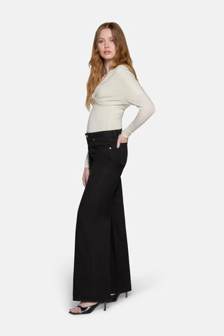 a women in front of whie background standing worn top and low rise baggy jeans in black by lkblue 