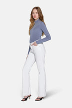 women in front of white background wearing white low rise boot cut jean. 