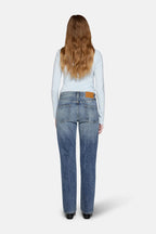 a women in front of white background wearing straight leg jeans in blue with back cover with hairs 