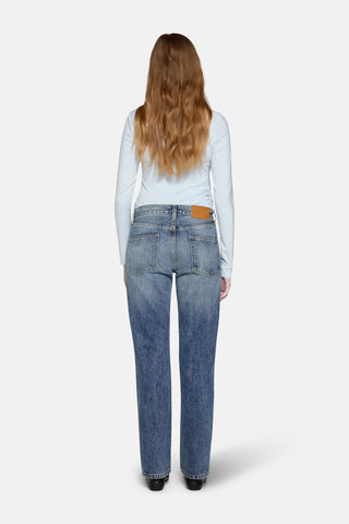 a women in front of white background wearing straight leg jeans in blue with back cover with hairs 