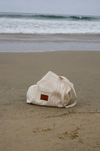 Beige bag on a sandy beach with ocean waves in the background