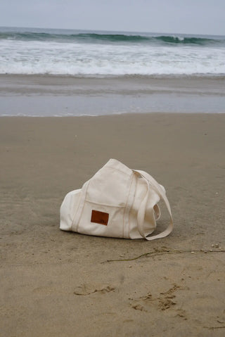 Beige bag on a sandy beach with ocean waves in the background
