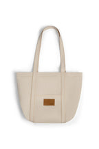 Beige denim tote bag with a brown leather patch on a white background