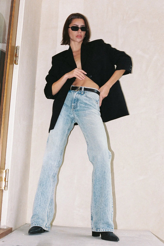 Person wearing a black coat and light blue jeans indoors.