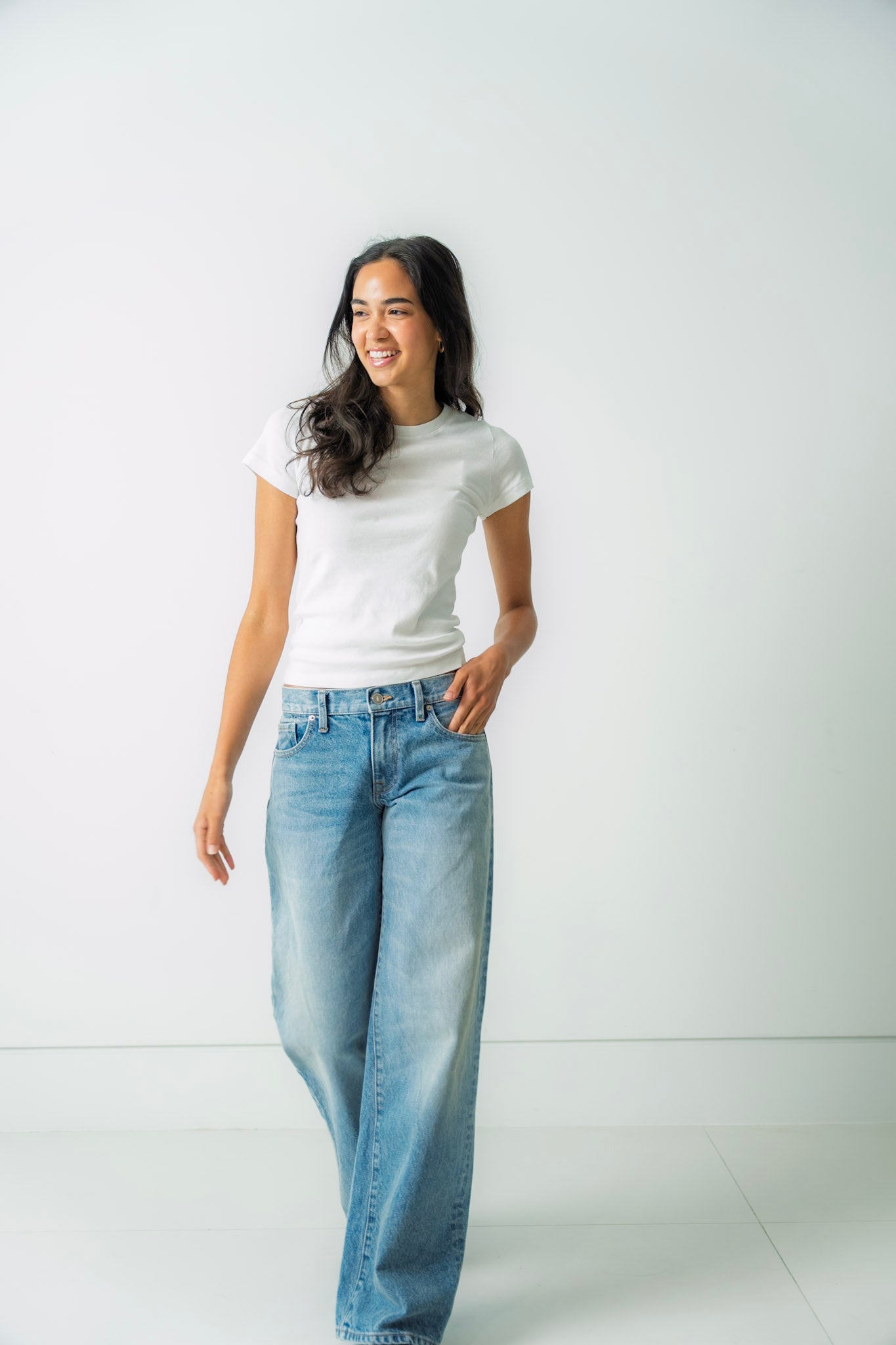 Woman wearing a white t-shirt and light blue bootcut  jeans against a white background