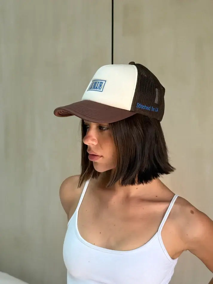 A person wearing a brown and white cap for women, against a plain background