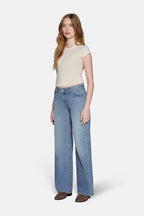 women in blonde hair wearing low rise baggy jean in blue with tight top in biegie