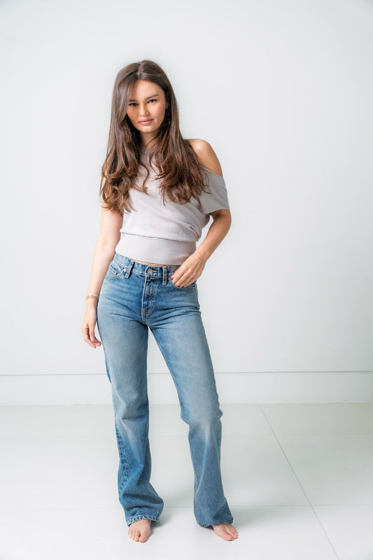 Woman wearing light blue jeans and a white top on a white background