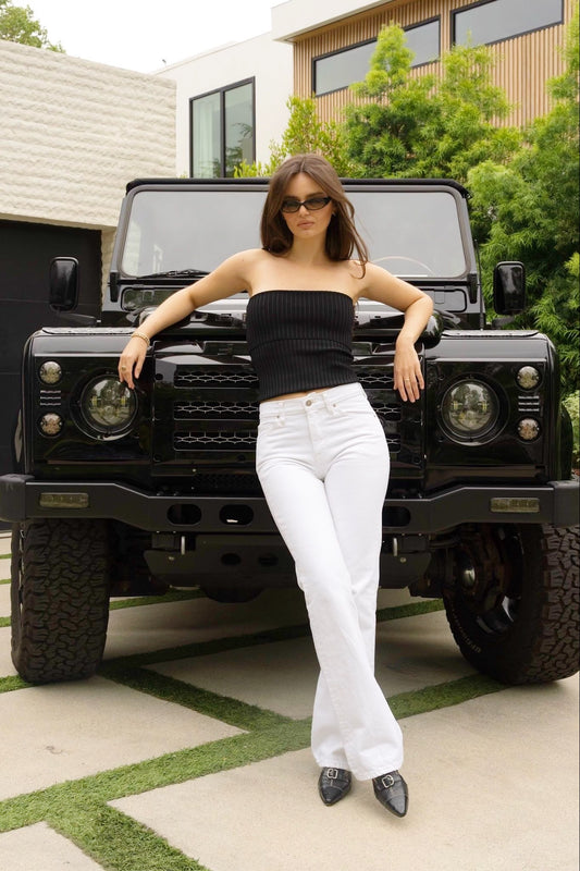 Woman posing in front of a black SUV in a white bootcut jeans women 