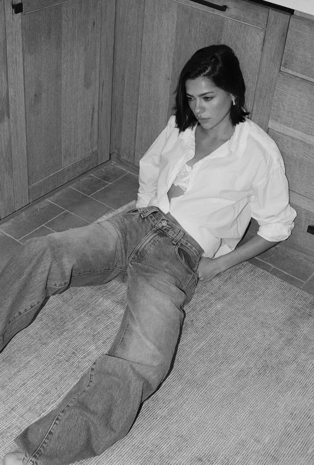 woman sitting on a tiled floor wearing a white shirt and jeans.